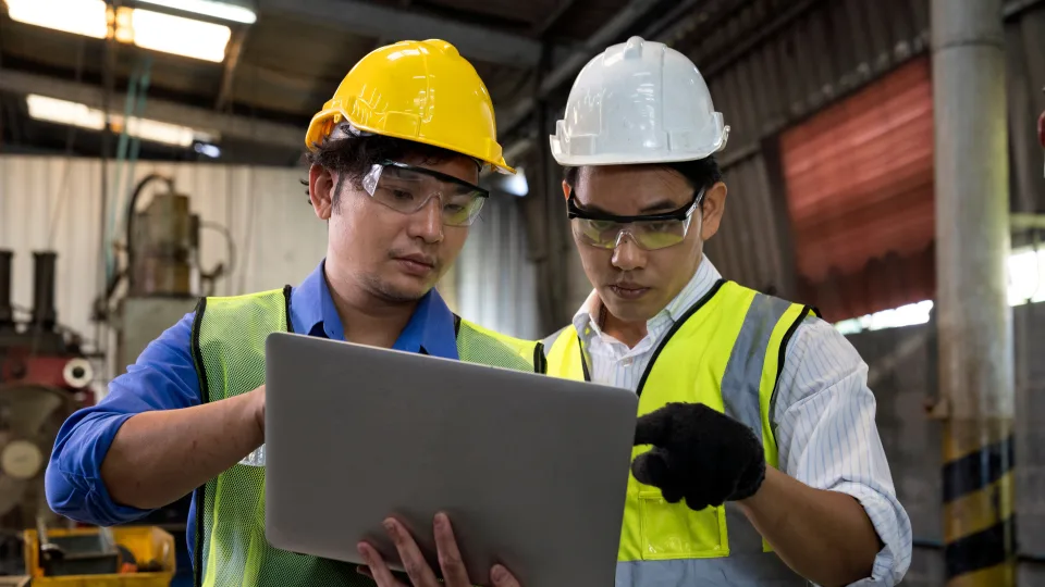 Two operators check a notebook at the factory
